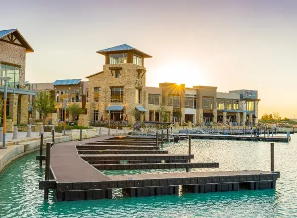 Sunset view of the Towne Lake boardwalk and waterfront shops in Cypress, TX, served by AsterSmiles dental office.