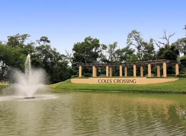 The Coles Crossing community entrance with a large fountain and pond in Cypress, TX, located near the AsterSmiles dental office.