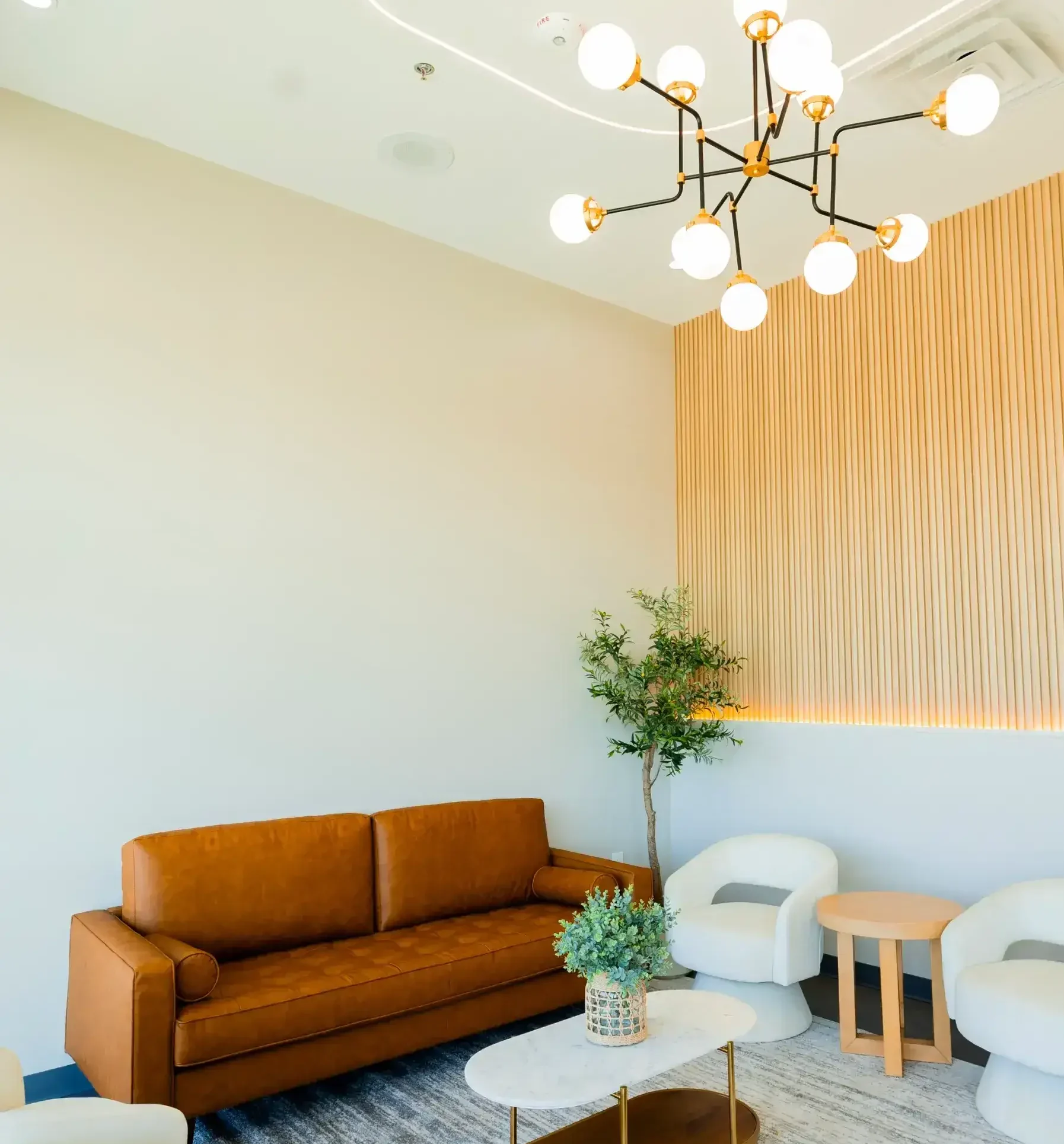Bright lounge area with an orange sofa, white bubble chairs, and a wooden slat wall. Modern dental operatory at Aster Smiles featuring digital imaging technology for bone grafting procedures in Cypress TX