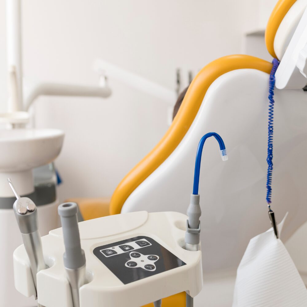 Dental chair with blue dental handpiece and control panel in a bright clinic room, ready for use
